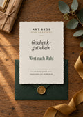 Art Bros Geschenkgutschein – Karte im Galerie-Stil auf Eichentisch mit grünem Umschlag